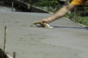 A man smoothing the wet concrete surface of a path