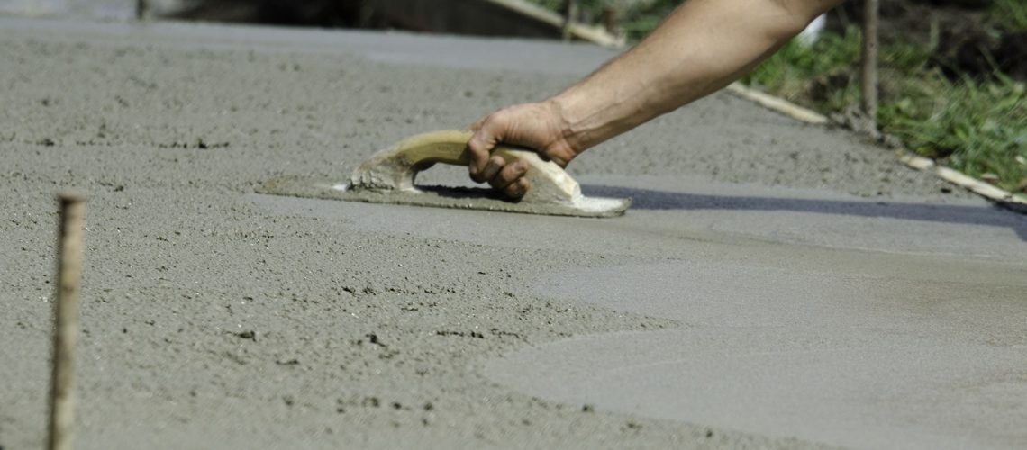 A man smoothing the wet concrete surface of a path